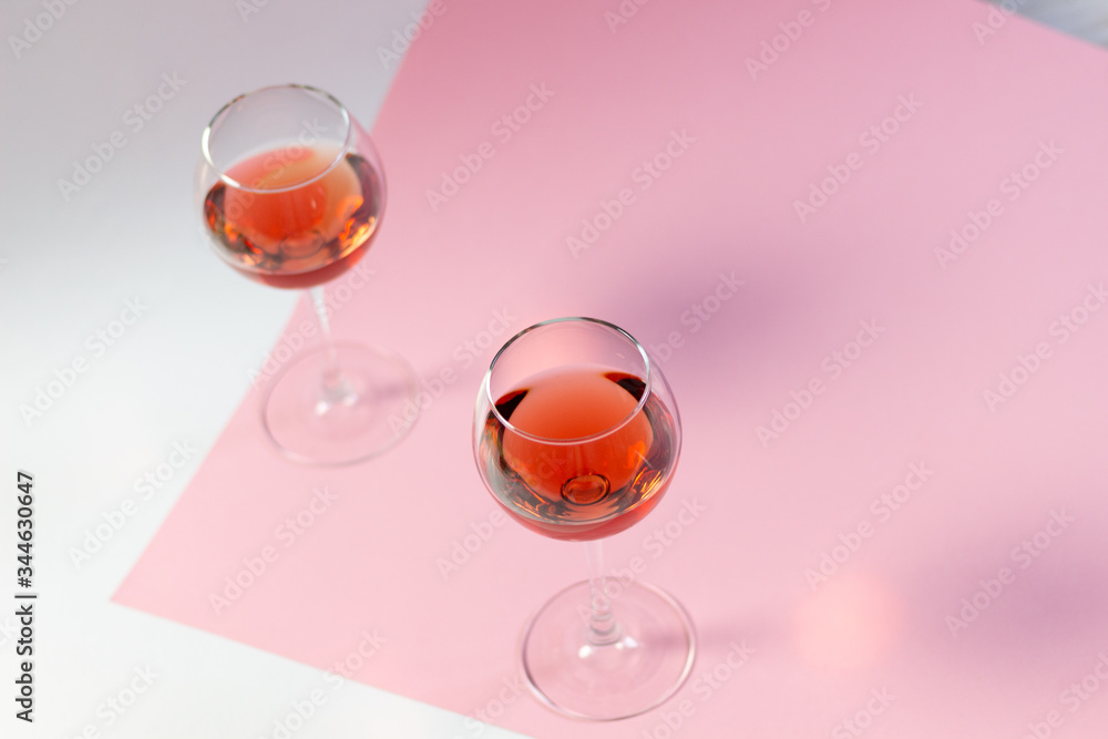 TWo glasses with rose wine standing on white and pink background TWo glasses with rose wine standing on white and pink background