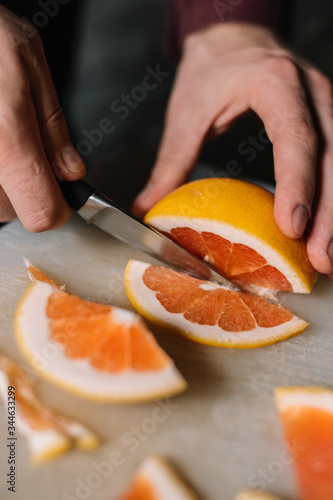 Grapefruit cutting process. A man holds a fruit in his hands. Close-up view.