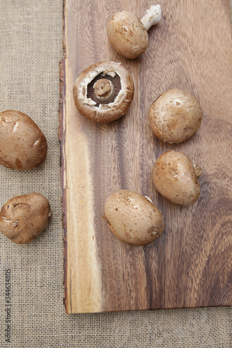 Flat lay fresh organic brown mushrooms champignon on a wooden board. Top view. Vertical photo. 