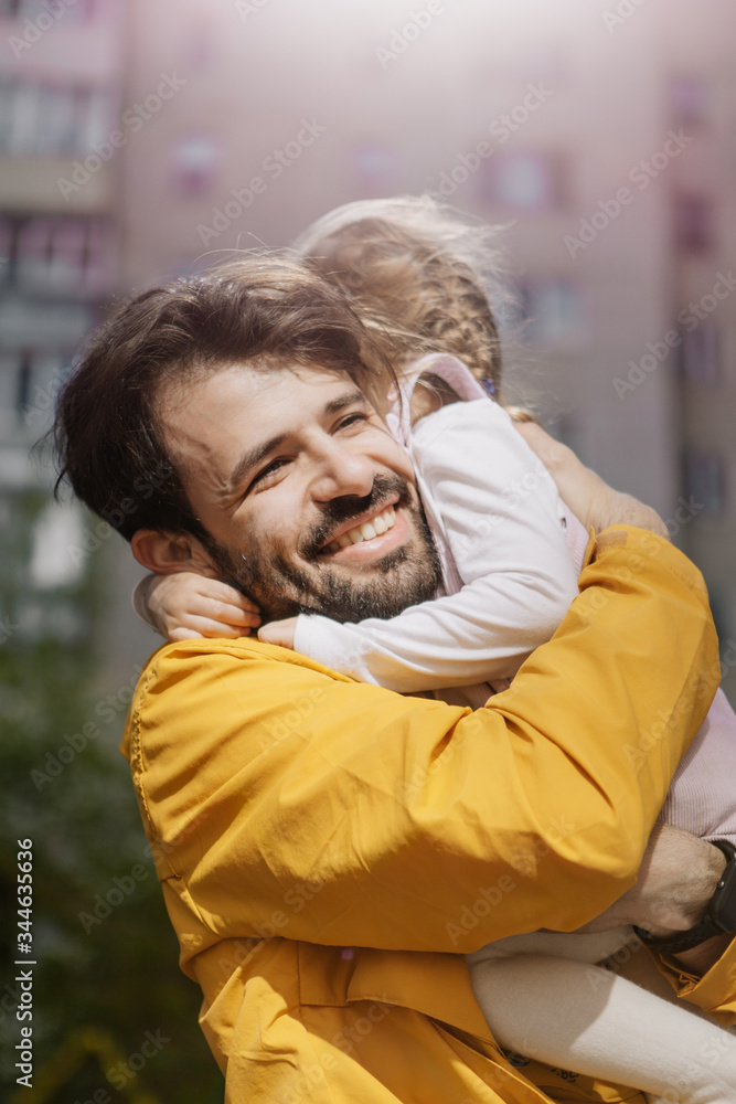 Portrait of a stylish pretty Father and his little daughter, they went for a walk on the playground in the courtyard of a multi-storey building Portrait of a stylish pretty Father and his little daughter, they went for a walk on the playground in the courtyard of a multi-storey building