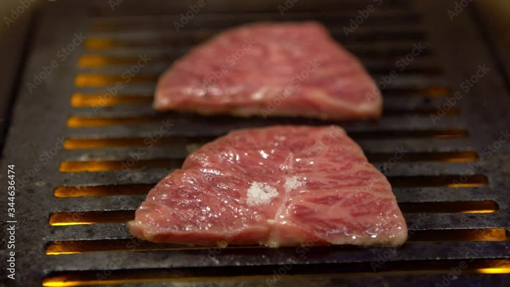 Slowmotion of thinly sliced Japanese wagyu beef on grille for barbecue