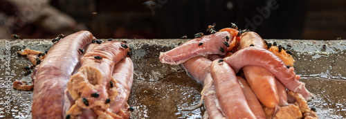 Fotografi many flies on fish guts on stone counter at the street fish market