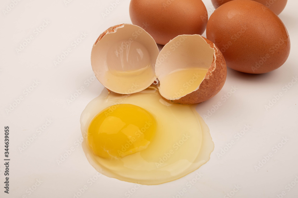 A broken chicken egg and scattered eggs on a white background. Close up. A broken chicken egg and scattered eggs on a white background. Close up.