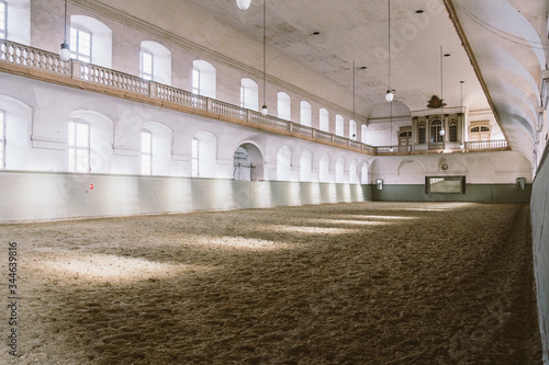 Royal manege with sand for horses in Denmark Copenhagen in territory Christiansborg Slot. Riding hall with sandy covering. Indoor riding facility at equestrian center. Horse arena interior photo