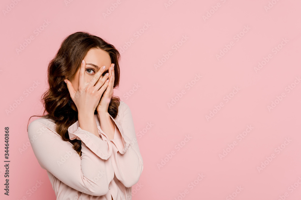 scared woman covering face and looking at camera isolated on pink scared woman covering face and looking at camera isolated on pink