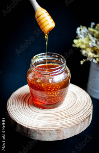 Honey dripping from a wooden dipper.