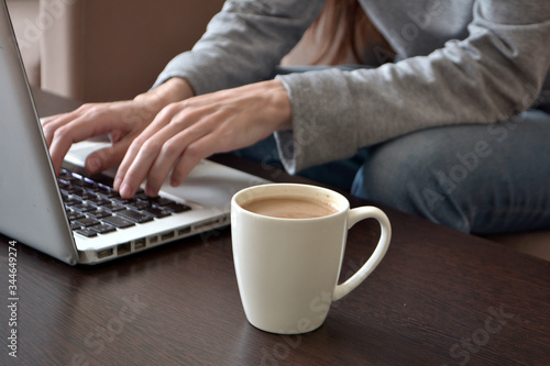 Online and remote work or home distance education concept. Close up of a young female freelancer working on a laptop from a home office