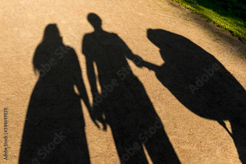 Silhouettes of a young happy family with a stroller with a newborn baby. Changes after the birth of a baby