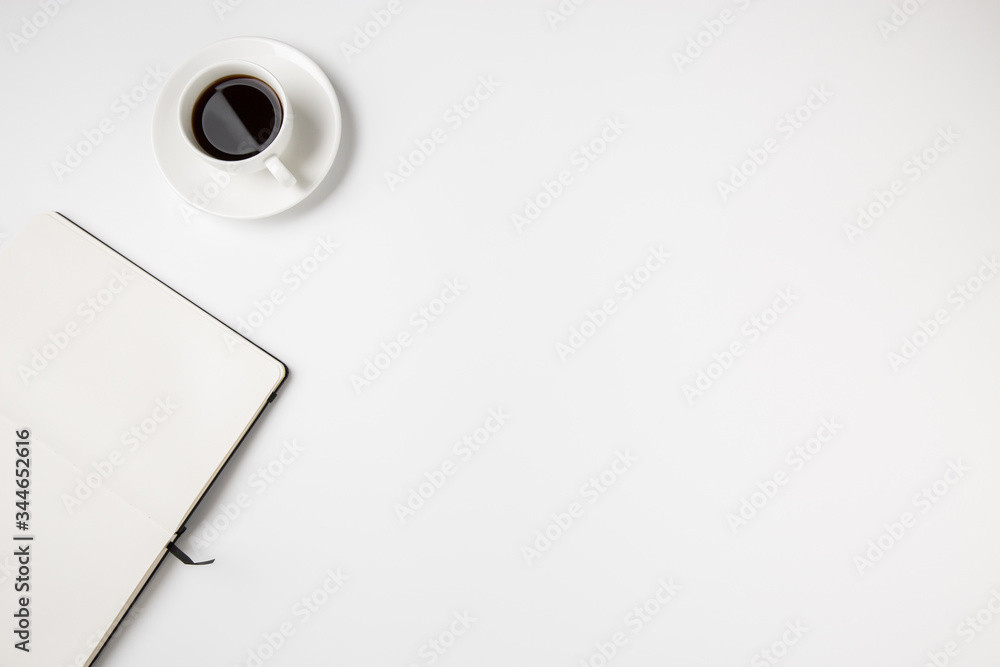 Abstract minimal white desk top with coffee cup and empty open notebook page Abstract minimal white desk top with coffee cup and empty open notebook page