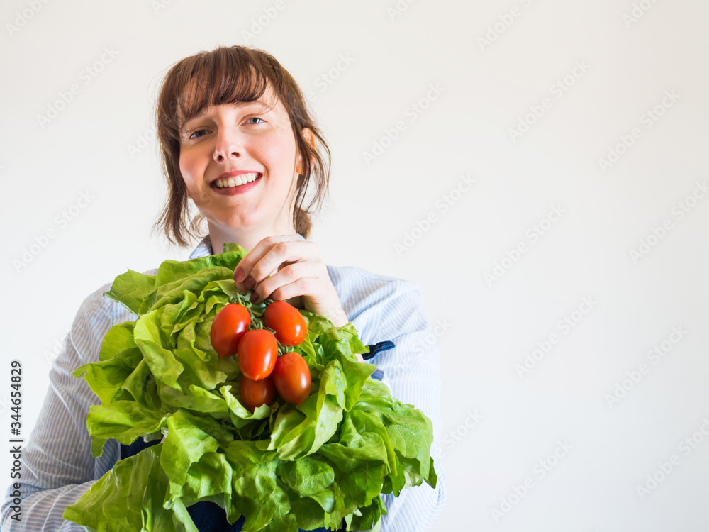Delivery girl or small shop owner wearing blue apron holding fresh produce - fresh vegetables, pasta and milk - in gloved hands. Food delivery, local grocery shopping Delivery girl or small shop owner wearing blue apron holding fresh produce - fresh vegetables, pasta and milk - in gloved hands. Food delivery, local grocery shopping