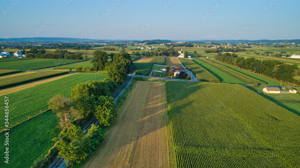 Aerial view of farm lands and corn crop with a train right of way in late afternoon