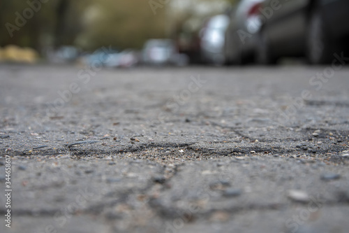 Cracked asphalt in the city, cracks and potholes on the road, taken from the bottom point, visible horizon line, selective focus.