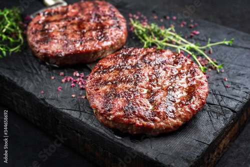 Cuadro en lienzo Barbecue Wagyu Hamburger with red wine salt and herbs as closeup on a charred wo