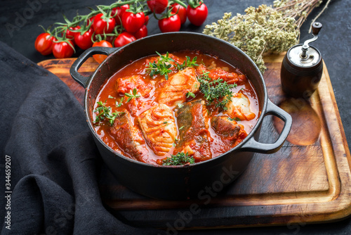 Traditional Brazilian fish stew moqueca baiana with fish filet in tomato sauce as closeup in a modern design cast-iron roasting dish photo