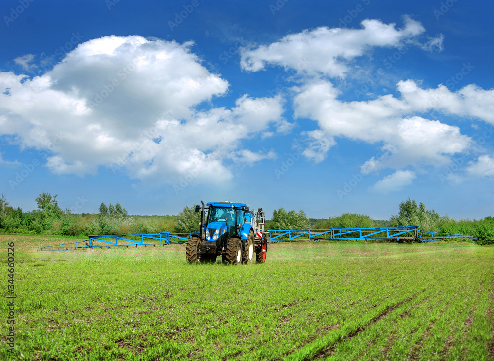 new blue tractor in field work with trailed sprayer, winter crop fertilizers, spring crop fertilizers new blue tractor in field work with trailed sprayer, winter crop fertilizers, spring crop fertilizers