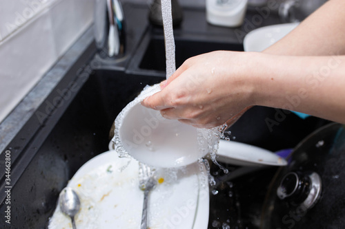 female hands wash dishes in the kitchen sink