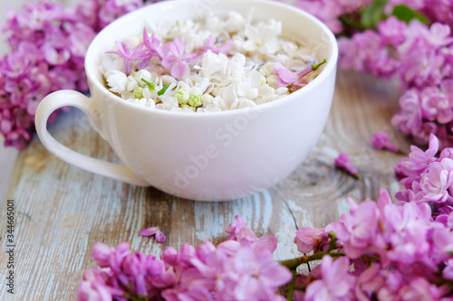 Cup of tea with lilac flowers on wooden background. Spring time. Vase with lilac. Copy space for text. The concept of holidays and good morning wishes. 