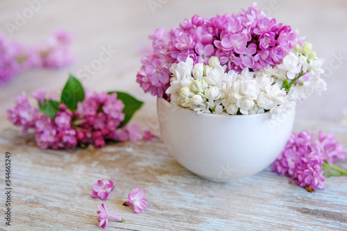 Cup of tea with lilac flowers on wooden background. Spring time. Vase with lilac. Copy space for text. The concept of holidays and good morning wishes. 