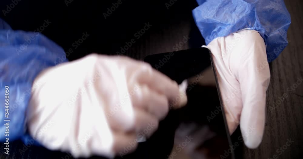 Young nurse cleaning her cellphone erradicating germs and to prevent COVID-19 contagion Young nurse cleaning her cellphone erradicating germs and to prevent COVID-19 contagion