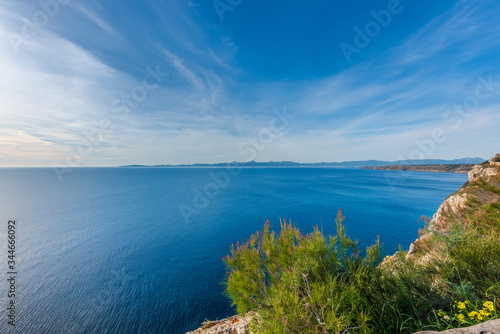 Views from a cliff to the bay of Palma de Mallorca, sky and blue sea, in the foreground some vegetation