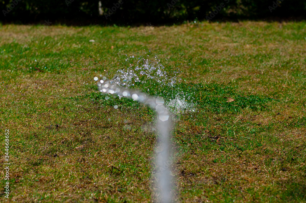 A stream of water irrigates a green lawn