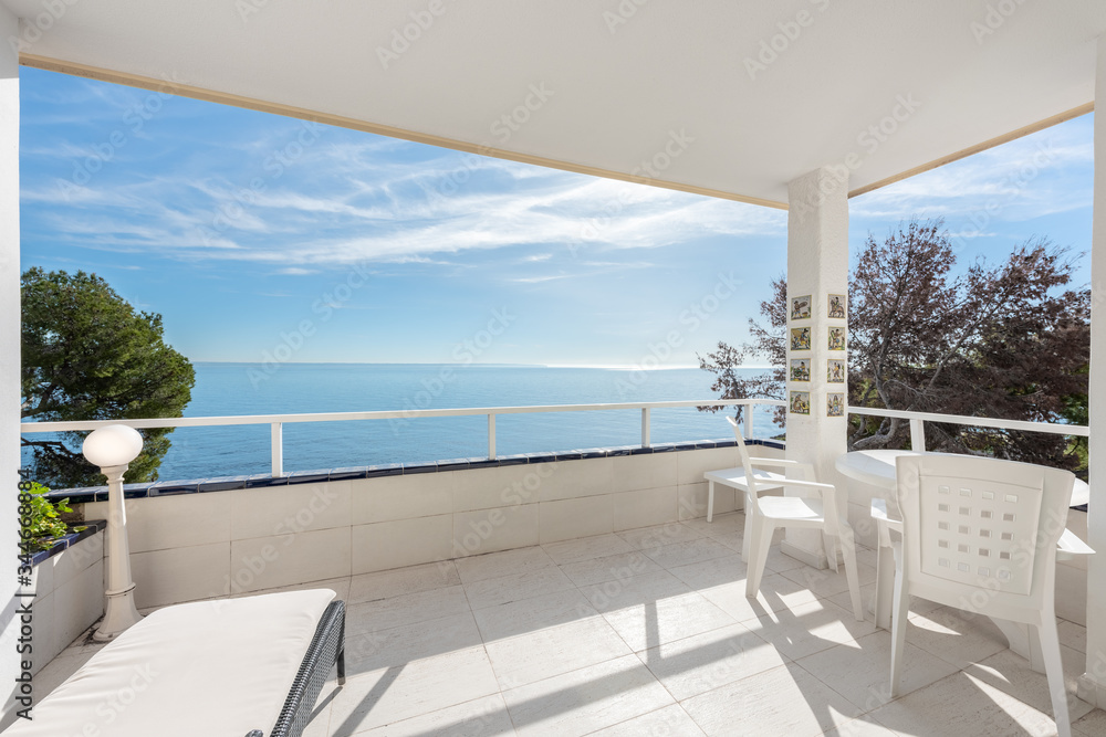 Fototapeta premium White covered terrace with white furniture, views of the sea with trees and blue sky,