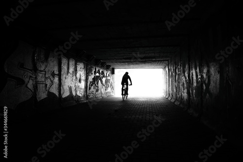 Light at End of Tunnel and Silhouette of Man Driving in Tunnel on bike