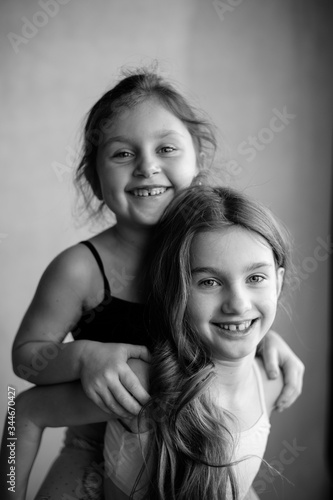Black and white portrait of two little systerichka girls hugging each other and laughing joyfully. Family values. Friendship. Joy