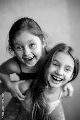 Black and white portrait of two little systerichka girls hugging each other and laughing joyfully. Family values. Friendship. Joy