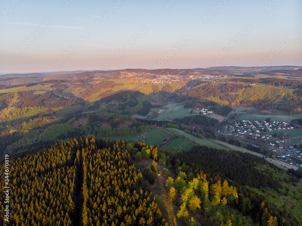 Luftaufnahme von den Wäldern des Sauerlandes bei Sonnenaufgang mit Winterberg im Hintergrund, Winterberg, Sauerland, Deutschland
