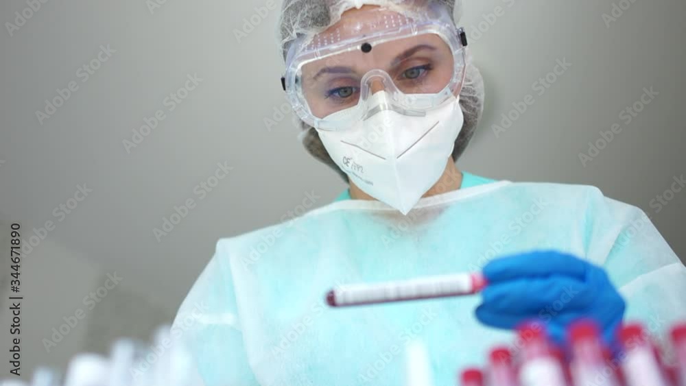 Beautiful girl laboratory assistant in the laboratory holds a test tube with a blood sample infected with coronovirus Covid-19. Diagnostics Sars-CoV-2 Beautiful girl laboratory assistant in the laboratory holds a test tube with a blood sample infected with coronovirus Covid-19. Diagnostics Sars-CoV-2
