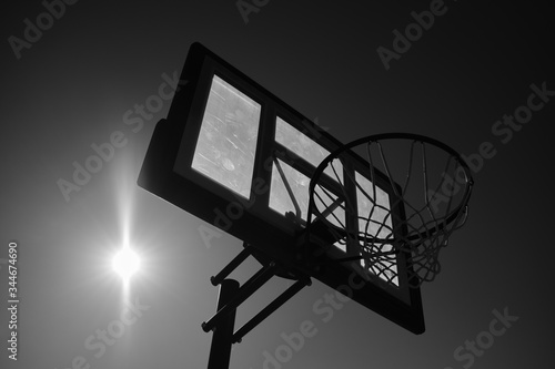 B+W image of backlit basketball hoop with sun flare in background