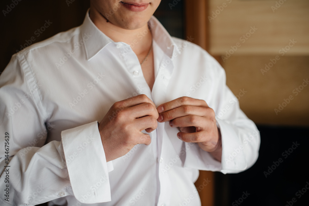 Stylish young man buttoning the cuff links on the sleeves. Style Stylish young man buttoning the cuff links on the sleeves. Style