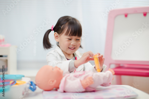 toddler girl pretend play doctor role  at home against white background