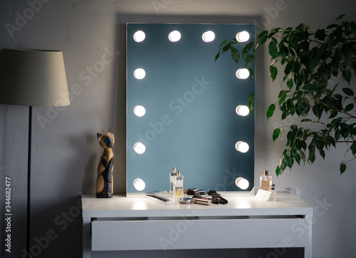 makeup mirror and cosmetics in the white dressing room with a tree and floor lamp