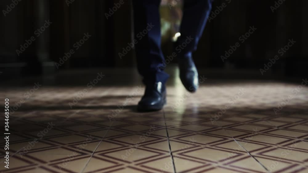 A man in leather black shoes is walking along a dark corridor front view, large plan A man in leather black shoes is walking along a dark corridor front view, large plan