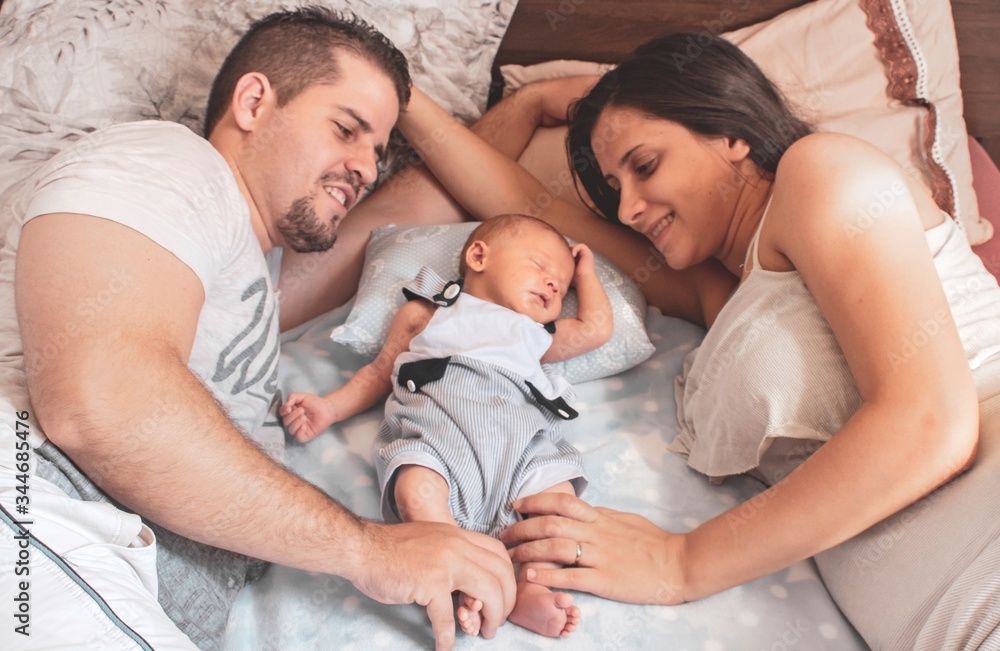 Parents lying in bed with baby, newborn sleeping Parents lying in bed with baby, newborn sleeping