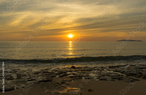 Brautiful golden sunrise scene with Hatta island on the horizon far away seen from campsite Besar island