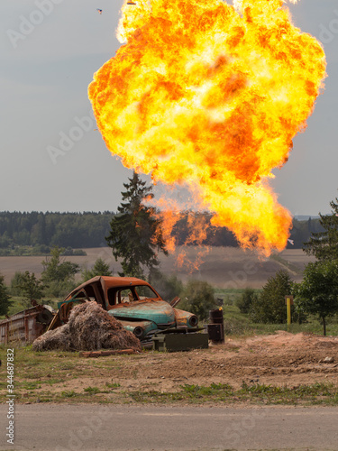 Explosion of a projectile near an old rusty car. A fire broke out next to a machine and a haystack. A show of military equipment. Demonstration performances.