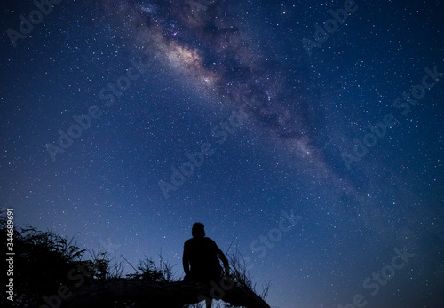 Person sitting on a tree branch at night enjoying milky way and sky full of stars dreamy moment at campsite in Sumbawa