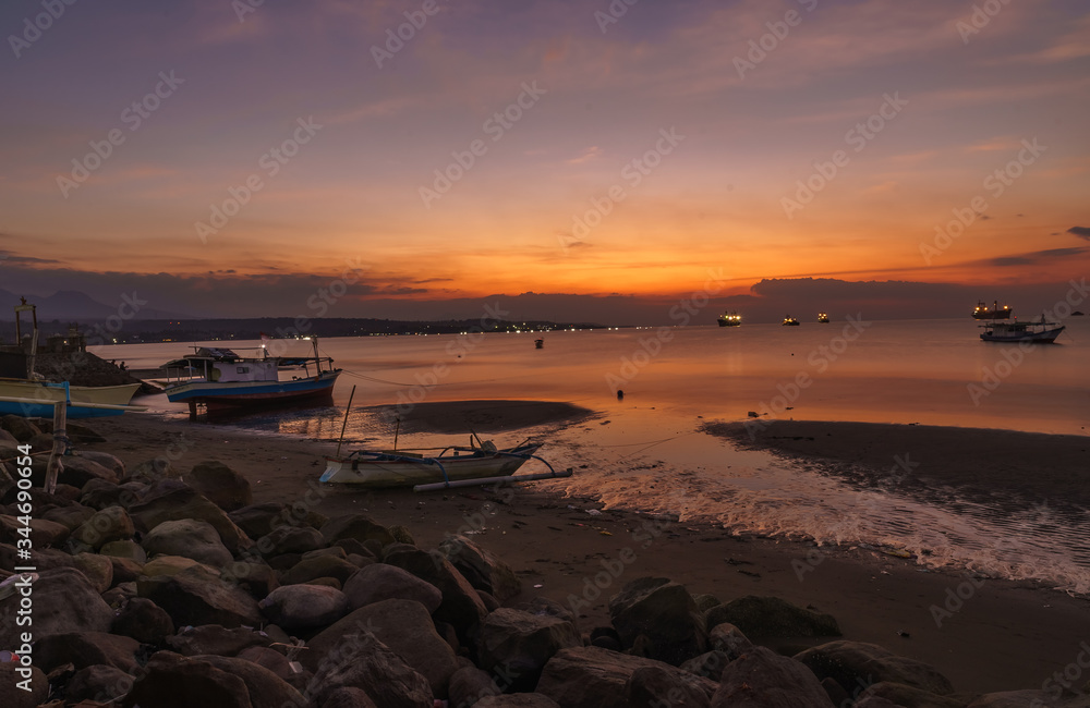 Sumbawa Besar town harbour scene in the evening glassy water long exposure many boats vivid colorful sunset