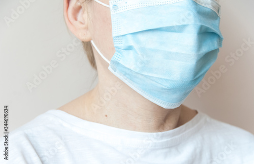 Close-up of female doctor or nurse wearing blue surgical medical mask and white suit. Isolated on pink background. Medical workers concept