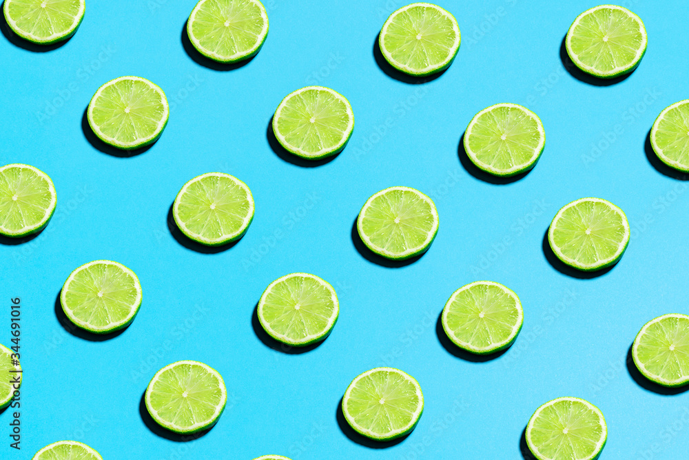 Lime pattern on bright light blue background. Minimal flat lay food texture. Summer abstract trendy fresh concept.