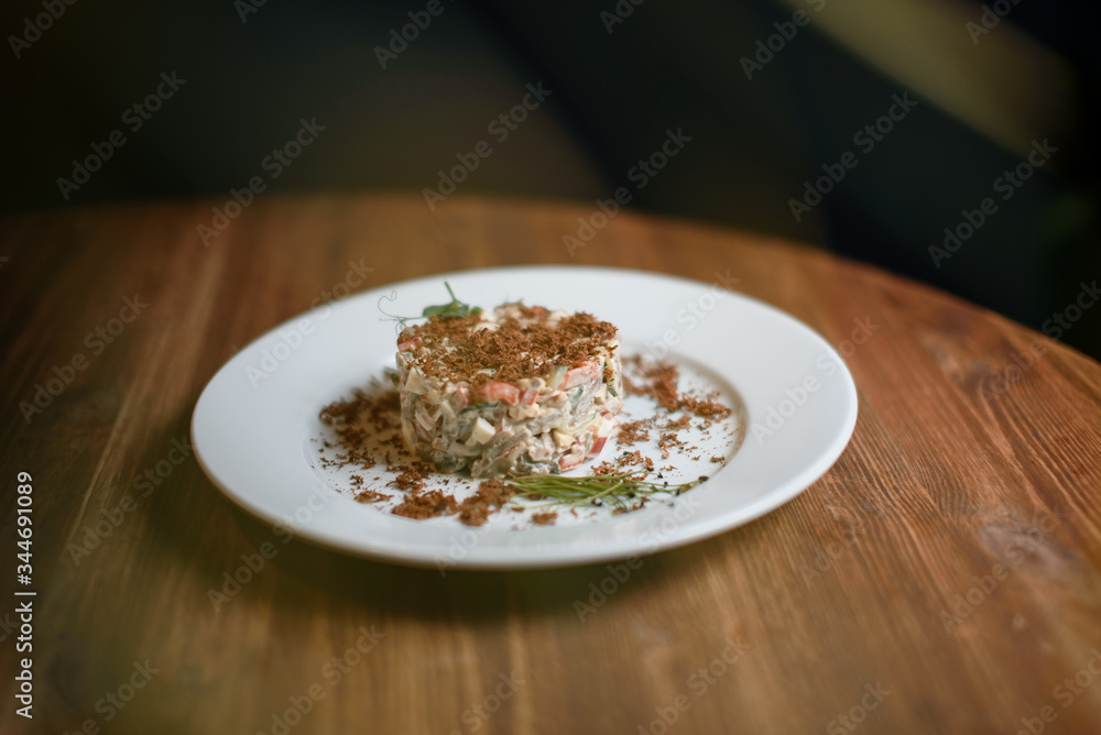 Olivier salad in a plate on the wooden table for restaurant