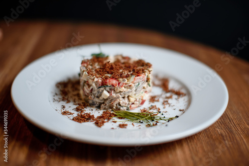 Olivier salad in a plate on the wooden table for restaurant