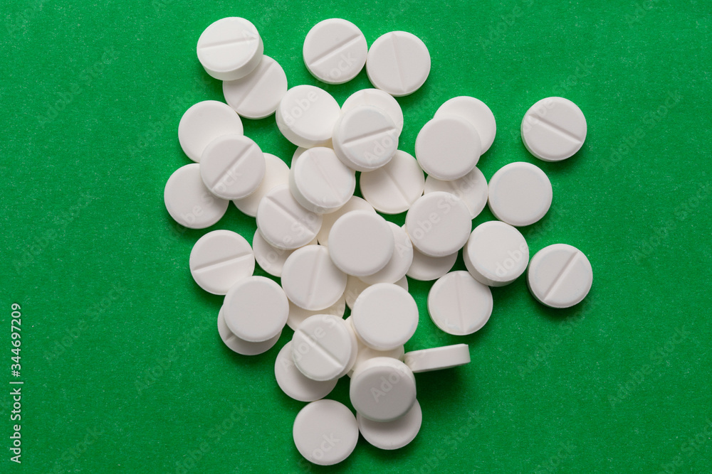 white pills scattered on a green background. white pills scattered on a green background.