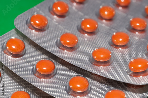 Orange pills in blister pack on green background