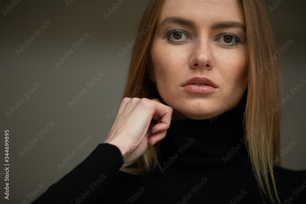 close up portrait of stylish looking girl in black turtleneck with blue eyes, model posing in interior, studio background 