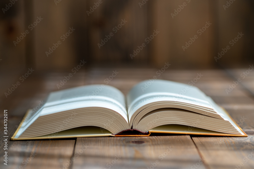 A thick book with open hardcover on a wooden floor A thick book with open hardcover on a wooden floor