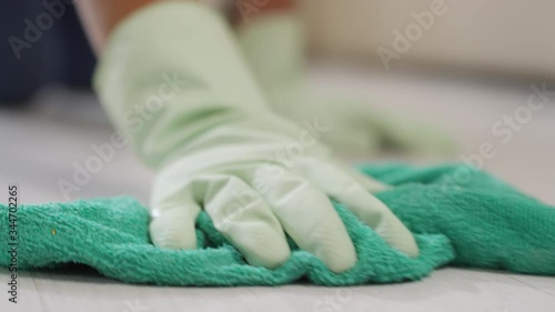 Close up of unrecognizable woman in gloves scrubbing floor with microfiber cloth